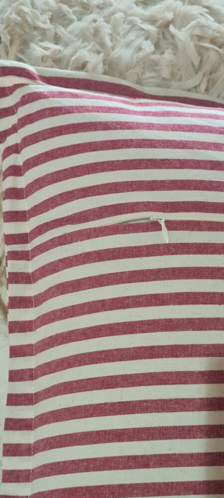 Detalle trasero con cremallera del cojín de rayas rojo y crema